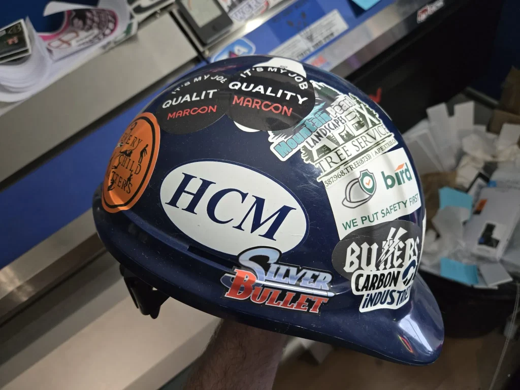 A hard hat covered in various colorful safety and company stickers
