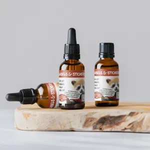 Three amber glass dropper bottles with labels are placed on a wooden surface